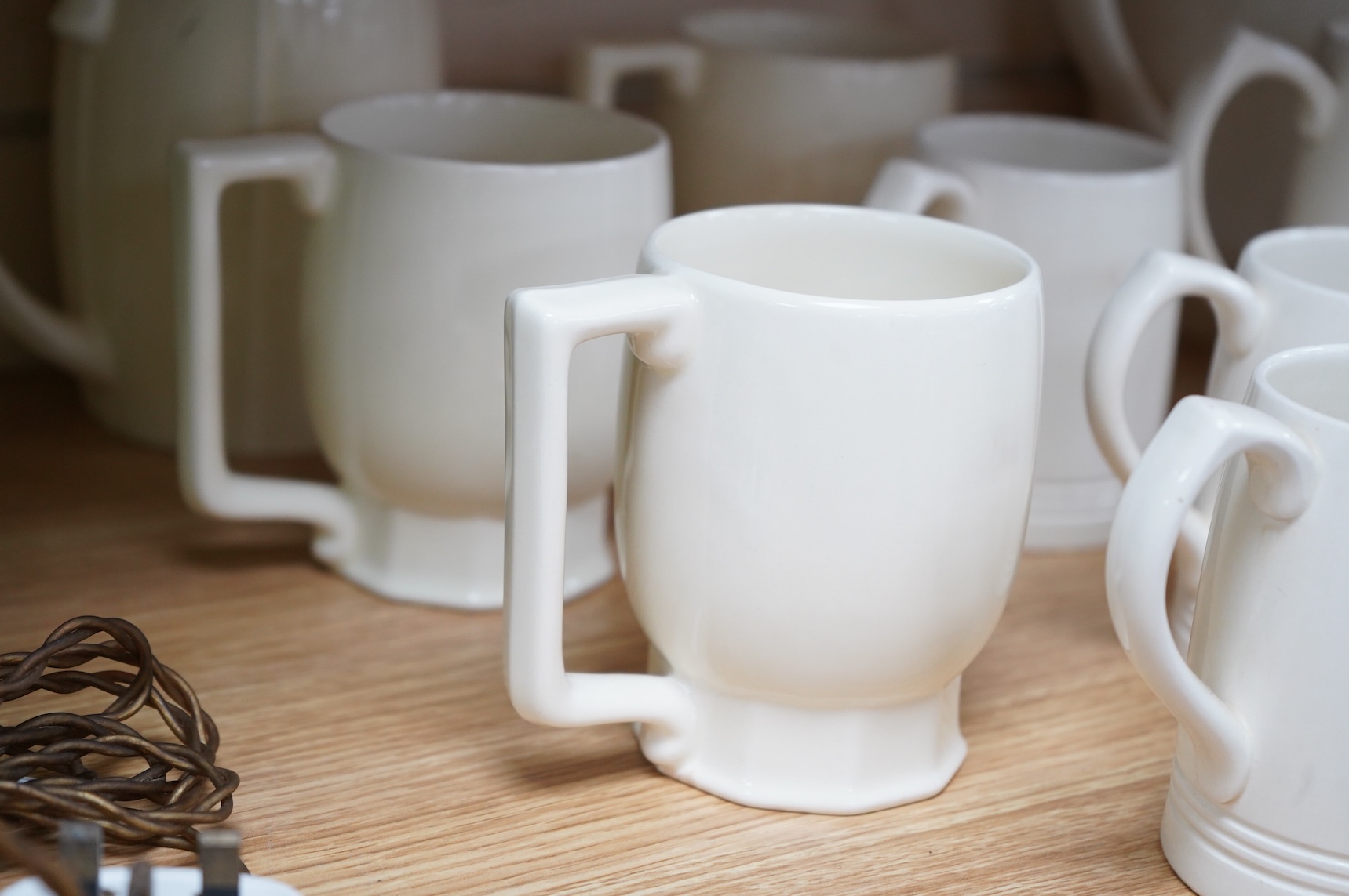 Keith Murray for Wedgwood, a cream lemonade jug, five small mugs, two large three faceted, largest 21cm high (12)